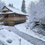 Holzhaus im verschneiten Winterwald mit Schneebedeckten Bäumen.